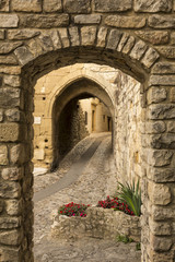 Narrow cobblestone street seen through stone archways in the historic village of Vaison la Romaine, Provence, France