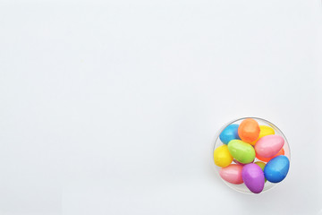 Aerial view of a bowl of colored eggs on a white background