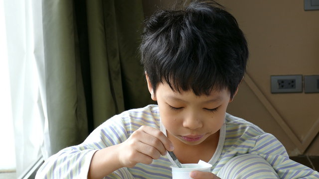 Young Asian boy eating yogurt in at home