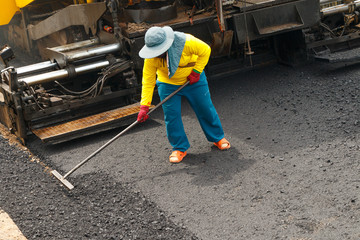 Close-up tracked paver at asphalt pavement works for road under construction.