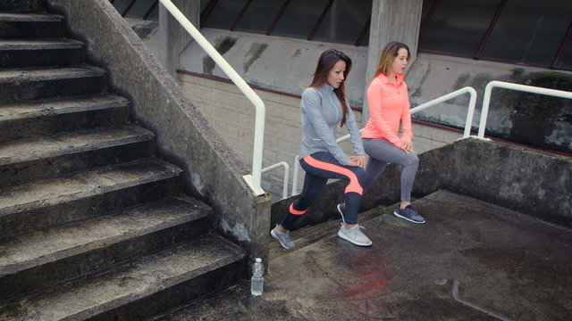 Fitness young women doing lunges workout on outdoor urban stairs. Female friends working out legs.