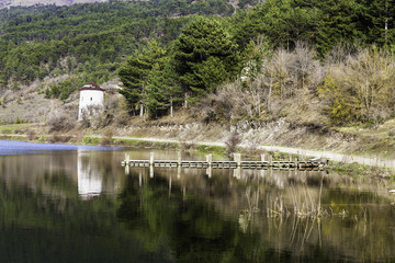 Fototapeta na wymiar Stone wind mill and wooden pier reflection on Cubuk lake near Goynuk, Bolu