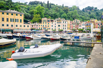 Pier and boats on bockground of colorful houses in bay of Portofino, Italy.