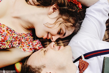 beautiful happy bride and stylish retro groom lying on tweed bla