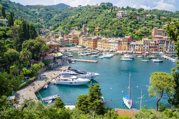 Fototapeta na wymiar Pier and boats on bockground of colorful houses in bay of Portofino, Italy.