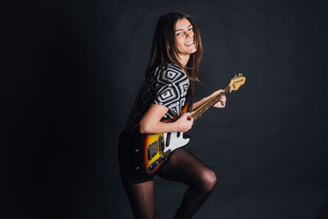 sexy girl with rock guitar on a black background