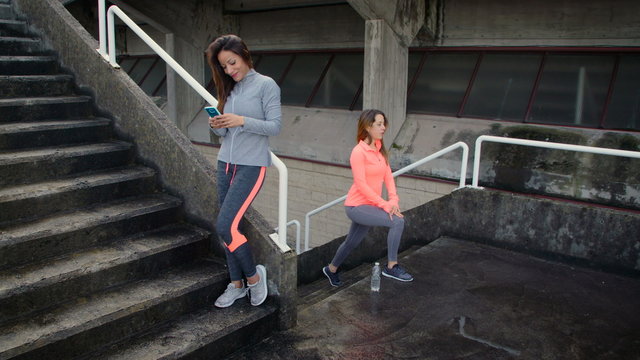 Fitness women working out doing lunges on city stairs. Outdoor urban workout concept. Female athletes training together. 