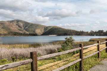 Fototapeta na wymiar Mountain range, lake and fence in foreground Otay Lakes County Park in Chula Vista, California.