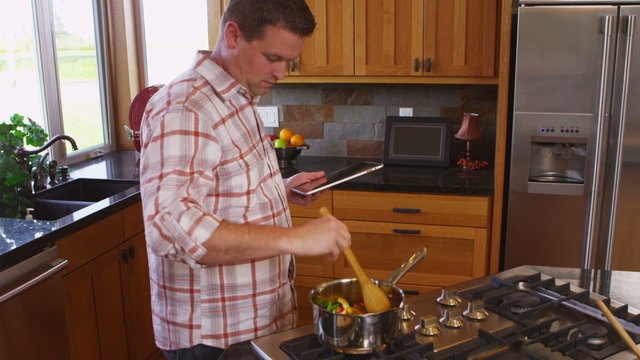 Man with digital tablet in kitchen cooking