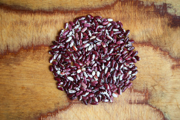 Kidney beans forming a round shape on a textured wooden background