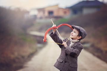 Adorable little preschool boy, shoot with bow and arrow at targe