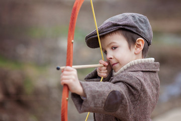 Adorable little preschool boy, shoot with bow and arrow at targe