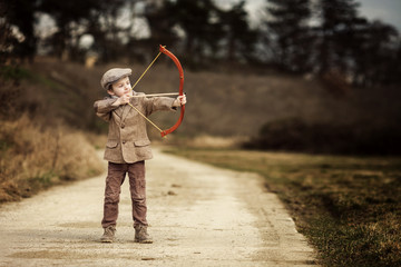 Adorable little preschool boy, shoot with bow and arrow at targe