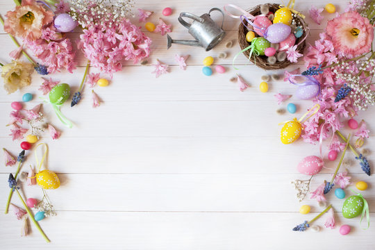 Easter white wooden background with flowers hyacinth, nest and colored eggs, space for text greeting