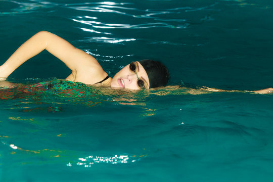 Woman athlete swimming crawl stroke in pool.