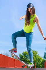 Teen girl skater riding skateboard on street.