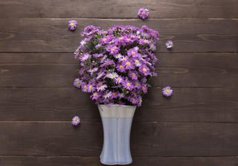 Purple cutter flower of the vase is on the wooden background