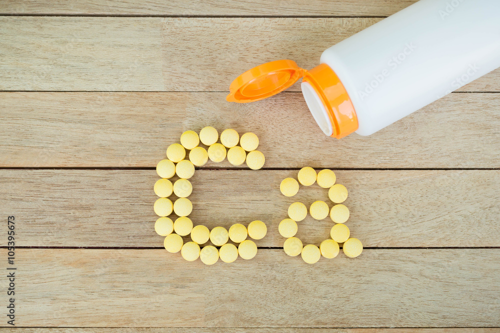 Wall mural yellow pills forming shape to ca alphabet on wood background