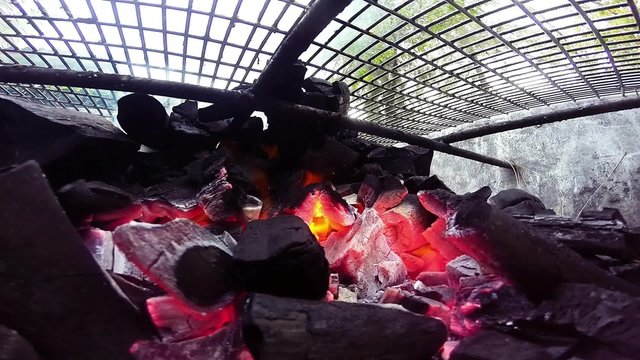 Burning charcoal under barbecue grille
