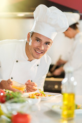 Portrait of a man chef putting sauce on a plateful