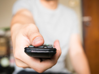 Close up of man pressing a button on remote control (shallow depth of field)