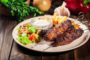 Grilled shish kebab served with fried chips and salad