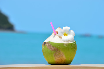 Tropical green coconut with drinking straw on wood table against - 105398439