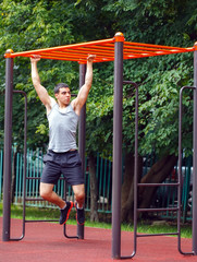 Fototapeta premium Muscular man doing pull-ups on horizontal bar