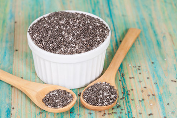 Nutritious chia seeds in bowl and spoon on a wooden