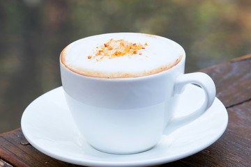 A cup of coffee in a white cup on wooden background