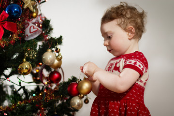 Kleines Mädchen dekoriert den Weihnachtsbaum