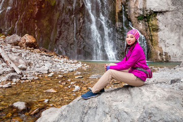The brunette girl at the waterfall in the mountains.Travel and leisure on holiday.