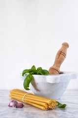 mortaio di marmo bianco con pasta, basilico e aglio: cucina italiana