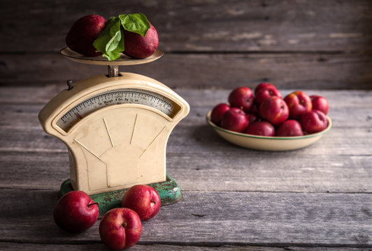 Blood plums on vintage scales against wooden background