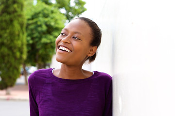 Happy young african woman leaning on wall