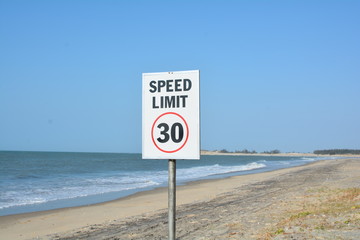 Speed Limit Sign with Thirty Kilometers, Miles Maximum, Sandy Desert, Wild Blue Ocean Shore, Blue Sky