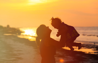 mother and little daughter play at sunset