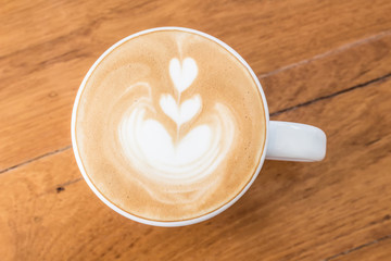 Cup of Art Latte coffee on the wooden desk