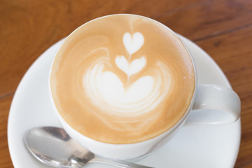 Cup of Art Latte coffee on the wooden desk