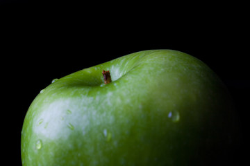 Green fresh ripe apple on black background closeup from side