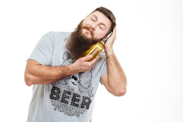 Bearded man with closed eyes enjoying bottle of beer