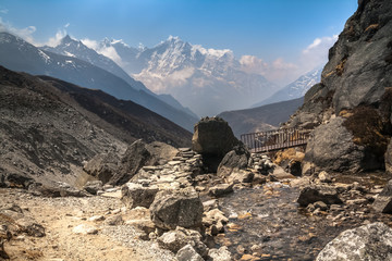Mountain trai  intersecting a small river on the bridgel in the