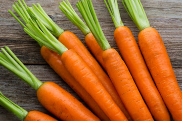 Fresh carrots bunch on rustic wooden background.