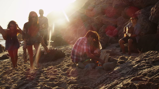 Group of young people at beach making camp fire