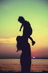 Fototapeta premium Silhouette of mother and child enjoying the view at riverside.