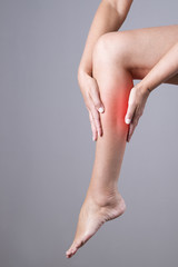 Pain in the calf muscle of the woman. Massage of female feet. Pain in the human body on a gray background © staras