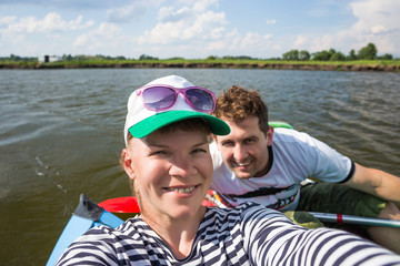 Fototapeta premium Young people doing selfie during kayaking on river in beautiful nature