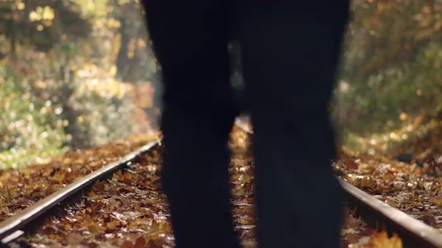 Man Jogging Down Train Tracks in Autumn Season with Leaves Falling Shallow Focus