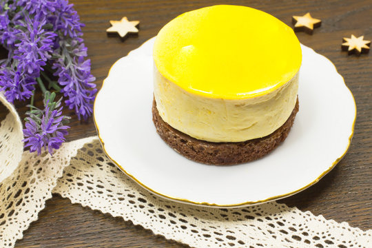 Round yellow cake on white saucer. Bands and lavender on the tab