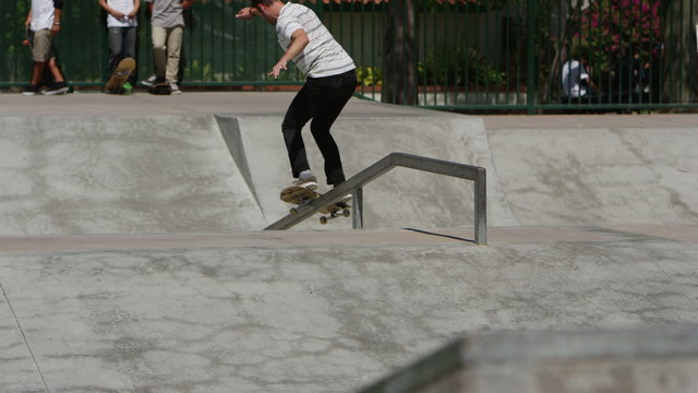 Skateboarder grinds rail at skatepark